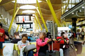 Família chegando ao aeroporto com documentos e dispositivos digitais, simbolizando planejamento e tecnologia para desembarque sem perrengues.
