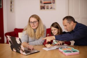 Família nômade digital usando dispositivos conectados para planejar viagem com inteligência artificial e equilibrar trabalho remoto e rotina familiar
