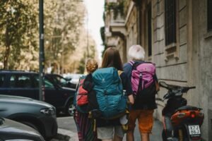 Família nômade digital com crianças usando laptops e tablets em ambiente de viagem, ilustrando tecnologia para trabalho e aprendizado remoto.
